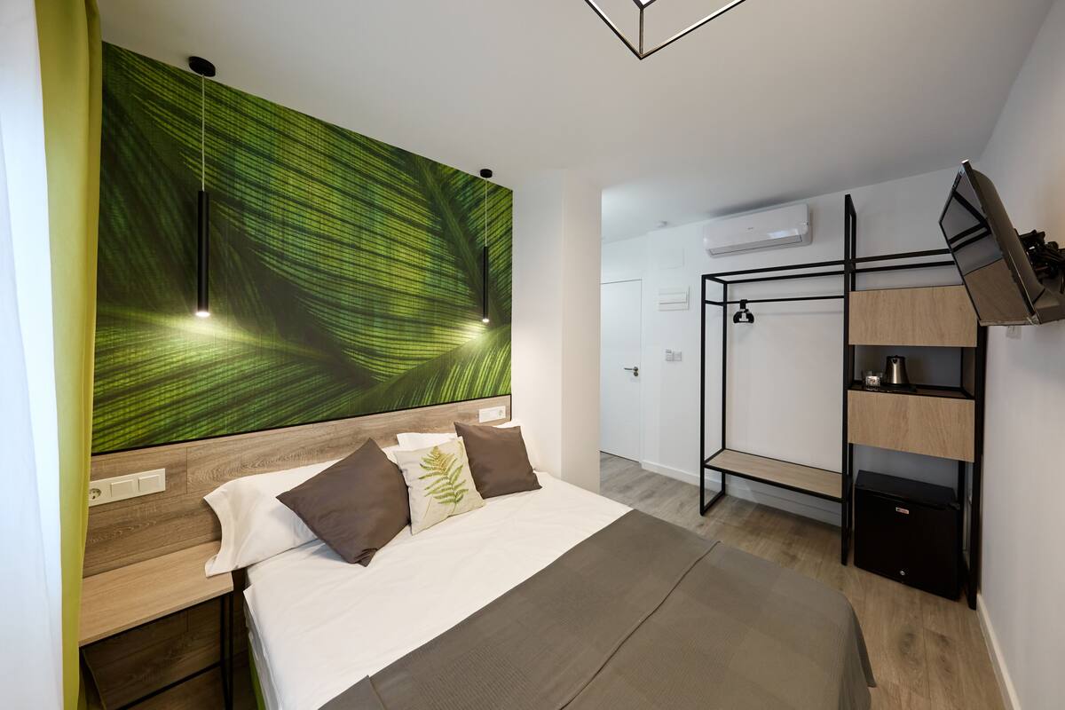 A modern bedroom with a bed, a wall-mounted TV, a bunk bed, and a wooden headboard.