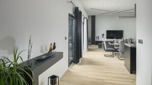 Una cocina moderna con comedor, suelo de madera y un amplio ventanal con cortinas.