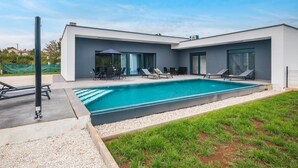 Una casa moderna con piscina, mobiliario exterior y zona de patio.