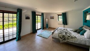 A spacious bedroom with a large bed, a window with curtains, and a view of greenery outside. - Typical house with swimming pool (Sao juliao)