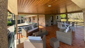 An outdoor covered patio area with stone walls, wicker furniture, and a wooden ceiling. - Typical house with swimming pool (Sao juliao)