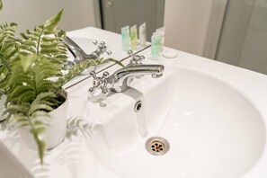 A bathroom sink with a modern faucet and a plant beside it. - Livestay - Hidden Covent Garden Gem (London)