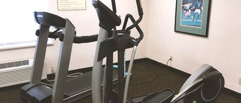 A fitness center with treadmills, elliptical machines, and a framed picture on the wall.