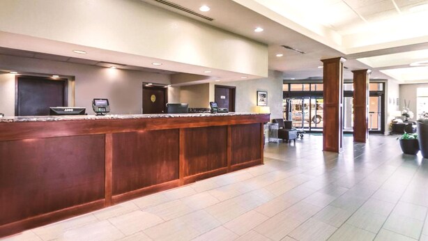 Ein Empfangsbereich mit Holztresen, einer digitalen Check-in-Station und Blick in die Lobby.