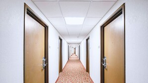 Ein Hotelgang mit Teppichmuster, Holztüren und einer Decke mit Einbauleuchten.