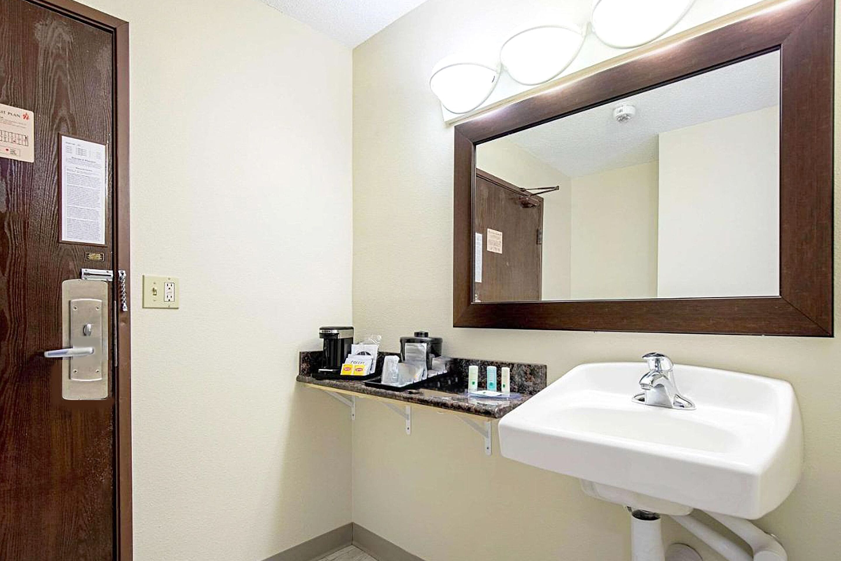 A bathroom with a white sink, a mirror, and a countertop with toiletries.