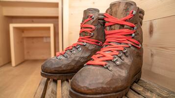 Un par de botas de senderismo marrones con cordones rojos sobre un banco de madera.