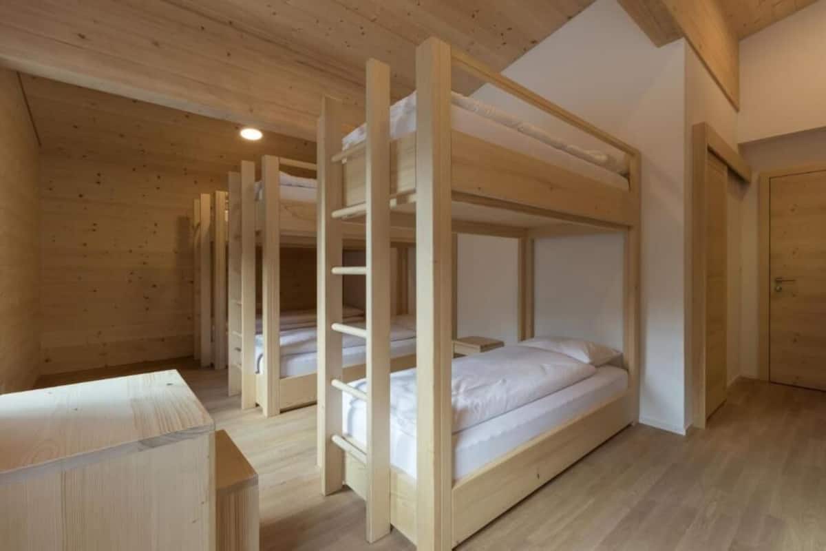 Une chambre avec un lit superposé en bois, un aménagement simple et un plafond en bois.