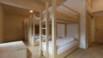 Ein Schlafraum mit einem Holzbett und einfacher Einrichtung, das von einer Holzwand gekrönt wird.