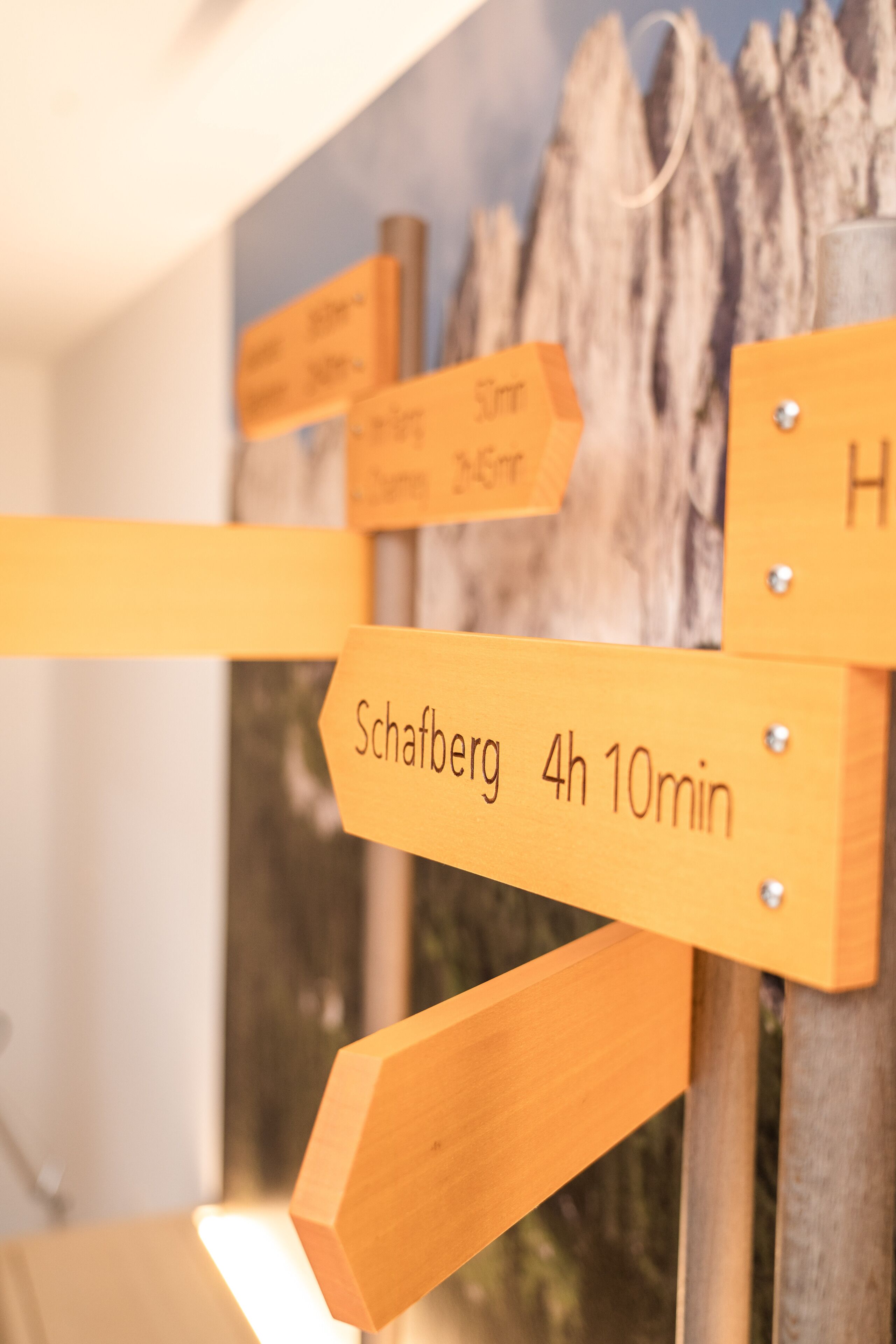 Ein hölzernes Wegweiser mit Pfeilen und Beschriftungen, die Entfernungen zu verschiedenen Orten angeben.