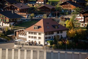 Um hotel com arquitetura alpina tradicional, com vários andares, telhado inclinado e um pátio com área de estar externa.