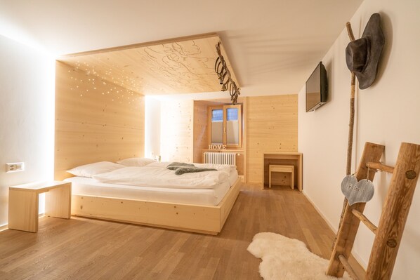 Une chambre à coucher au style minimaliste, avec un lit en bois, une petite table de chevet, un radiateur et un miroir au mur.