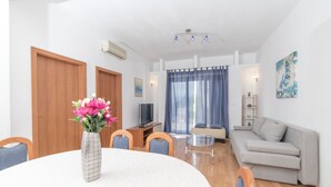 A modern living room with a round dining table, a sofa, and a TV. - Apartments Pavla i Niko (Lokva Rogoznica)
