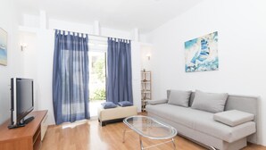 A modern living room with a sofa, a glass coffee table, a TV on a wooden stand, and a bookshelf. - Apartments Pavla i Niko (Lokva Rogoznica)