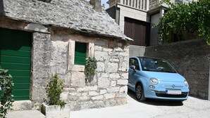 Un coche azul claro estacionado frente a un edificio de piedra con una puerta de contraventana verde.