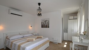 Un dormitorio con cama, mesitas de noche, escritorio, silla, armario y aire acondicionado.