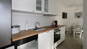 Una cocina moderna con armarios blancos, encimera de madera, horno empotrado y cafetera.