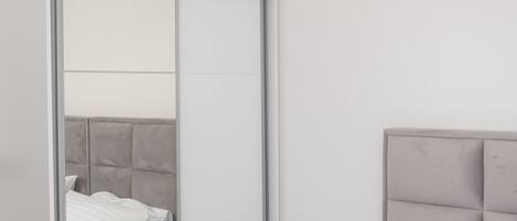 A bedroom with a bed, a wardrobe with a mirror, and a headboard.