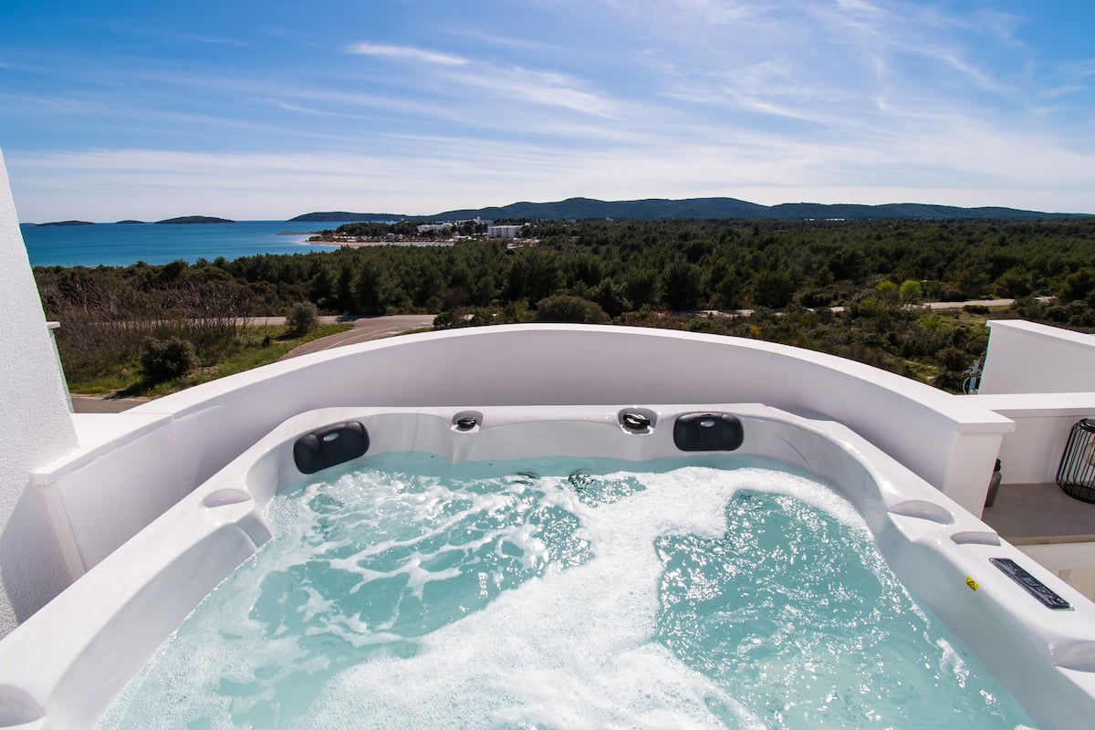 A hot tub with a view of the sea and hills.