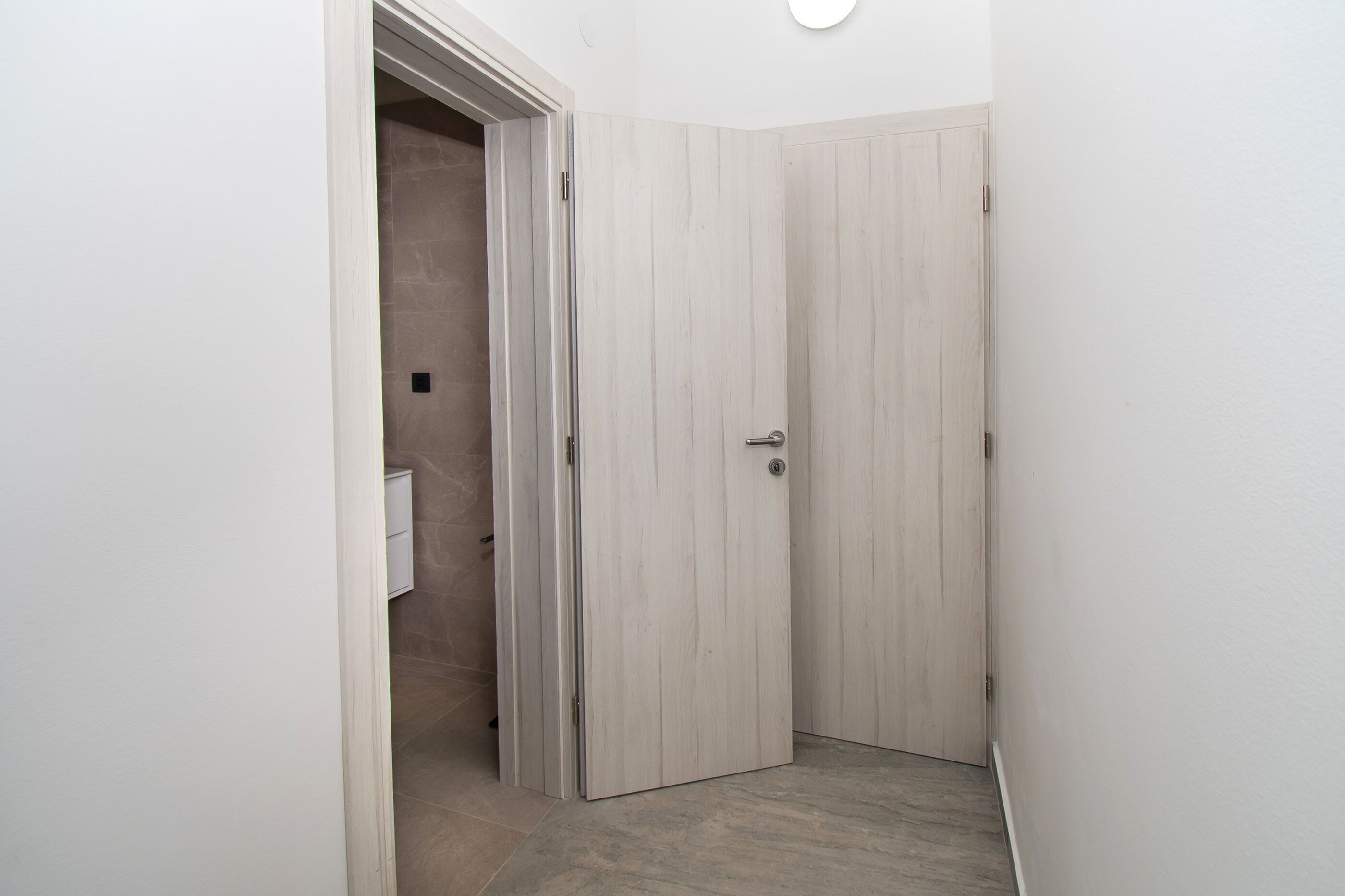 A narrow hallway with a wooden door and a white wall.