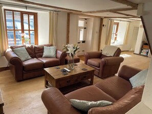 Relax in this stylish living room with a high ceiling, leather sofa, and wooden coffee table.