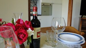 A dining table with a bottle of Chianti Classico wine, a glass, and a plate set.