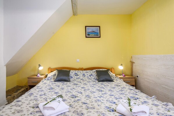 Una camera da letto con un letto, due lampade sui comodini, un comodino, una testiera in legno e un quadro appeso al muro.