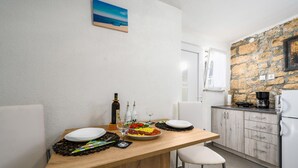Una cucina moderna con un tavolo di legno apparecchiato per due persone, una parete in pietra e un quadro raffigurante una spiaggia.