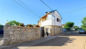 Una casa a due piani con un muro in pietra e un cancello in metallo.