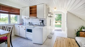A modern kitchen with white cabinetry, a built-in stove, and a coffee maker. There is a dining table with chairs and a bench. - 1 bedroom cozy apartment in Gullspång (Gullspång)