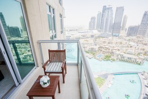 A balcony with a table and chairs, overlooking a cityscape and a body of water.