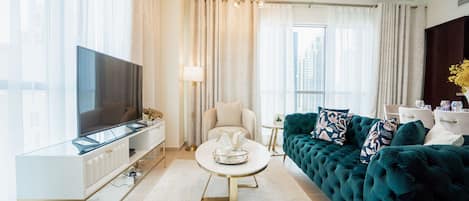Un salon moderne avec un téléviseur à écran plat, une table basse ronde, un canapé turquoise à motifs et une console blanche.