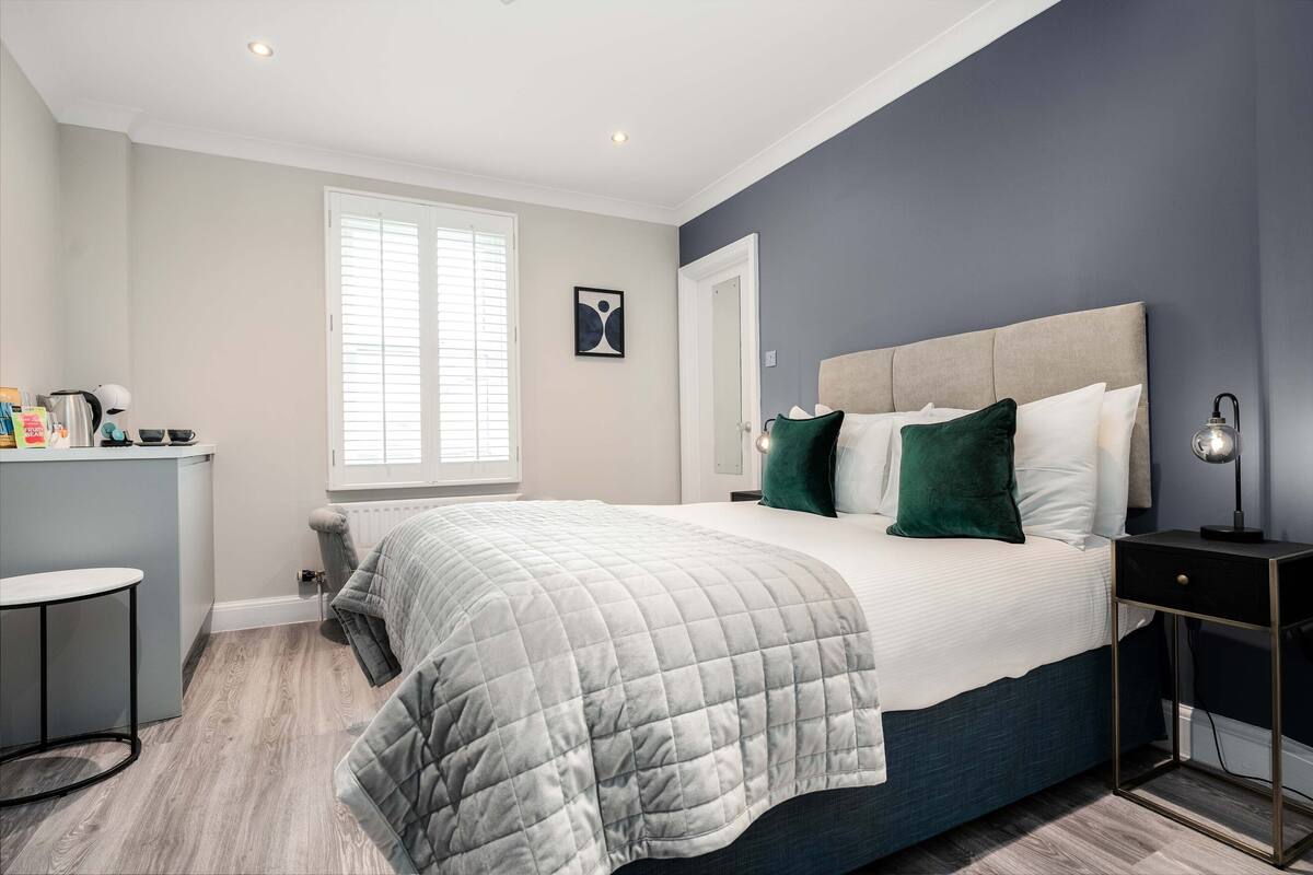 Une chambre à coucher avec un lit, une table de chevet et une fenêtre avec des stores.