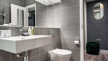 A modern bathroom with a white sink, a mirror, and a toilet.