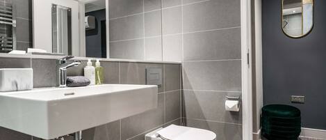 Un baño moderno con un lavamanos blanco, un espejo y un inodoro.