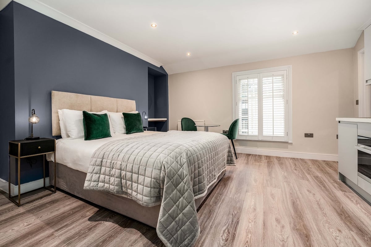 Une chambre à coucher avec un lit, des tables de chevet, une chaise et une fenêtre.