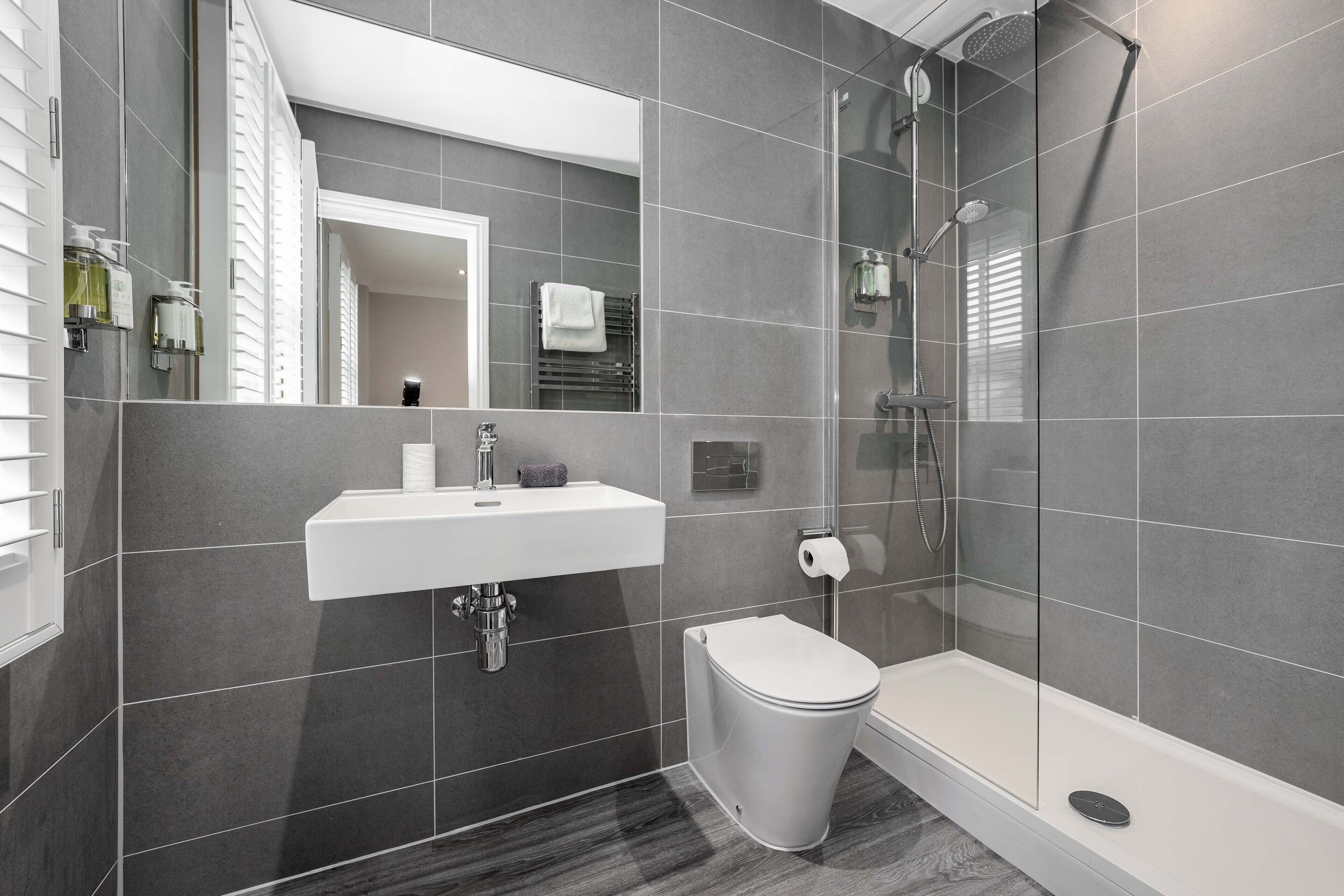 Een moderne badkamer met een wit wastafelmeubel, toilet en douche.