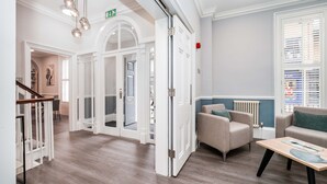 A spacious lobby with a wooden floor, a staircase, and a seating area with two sofas and a table. - The Regent Aparthotel (Cambridge)