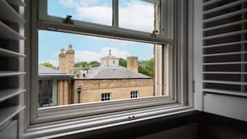 A window with a view of a building with brick walls and chimneys.