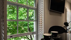 A room with a large window, a flat-screen TV, and a table with two cups. - The Regent Aparthotel (Cambridge)