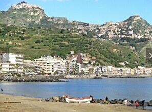 A coastal town with a prominent hill, a church, and a boat on the shore.