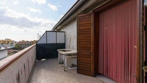 En balkong med en toalett, ett svart skåp och en röd gardin.