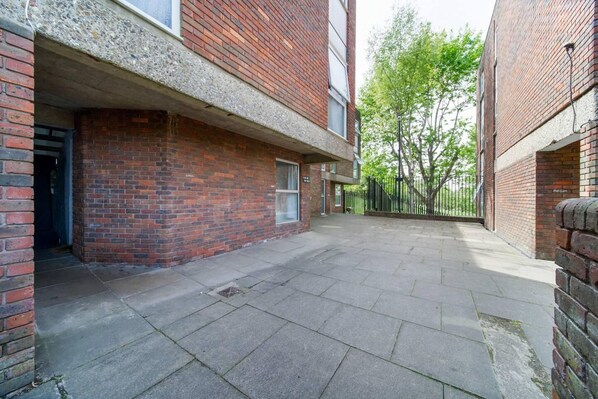 A courtyard with a brick building, a metal gate, and a tree.