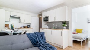 Kompakti oleskelutila, jossa on pieni keittiönurkkaus, sohva ja sänky.