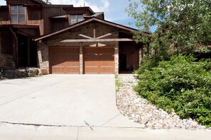 A two-story house with a stone facade and wooden garage doors. - Largest Black Bear Townhome - Private Hot Tub - EV Charger - Ski Shuttle (Durango)