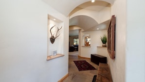 Un couloir avec un banc en bois, un tapis et une paire de bois de cerf accrochée au mur.