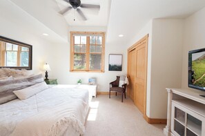 A bedroom with a bed, a chair, a desk, a television, and a window with a view of trees. - Largest Black Bear Townhome - Private Hot Tub - EV Charger - Ski Shuttle (Durango)