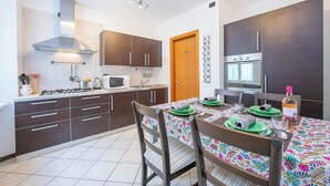 A modern kitchen with dark cabinets, a stainless steel range hood, a microwave, and an oven. - Casa Azzurra 150m From Lake Garda (Riva del Garda)