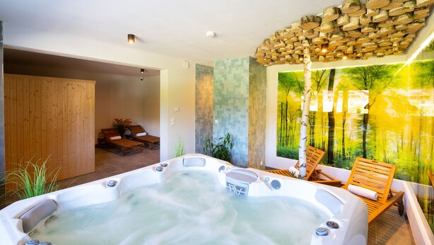 A spa area with a hot tub, wooden seating, and a mural of a forest. - Aparthotel pod Stokiem (Szczyrk)