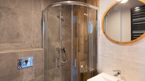 A modern bathroom with a glass-enclosed shower, a round mirror, and a white sink. - Aparthotel pod Stokiem (Szczyrk)